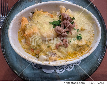 Rich baked seafood dish featuring cheese crust and parsley garnish 137205261
