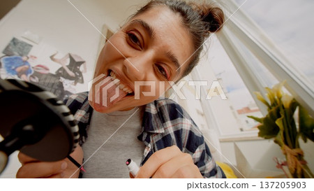 Casual and cheerful scene of woman jokingly making faces at mirror Casual and cheerful scene of woman jokingly making faces at mirror 137205903