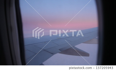 Airplane wing view from window during sunset with colorful sky Airplane wing view from window during sunset with colorful sky 137205943