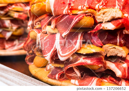 traditional Spanish bocadillos with Iberico jamon laid out in a slide on a shop window traditional Spanish bocadillos with Iberico jamon laid out in a slide on a shop window 137206652