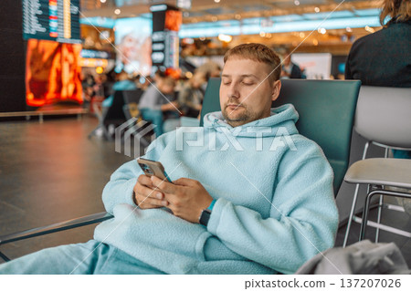 Male traveler waiting at airport terminal with luggage Male traveler waiting at airport terminal with luggage 137207026