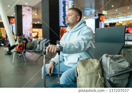 Male traveler waiting at airport terminal with luggage 137207037
