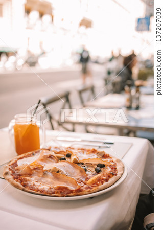 Italian pizza and orange juice on outdoor restaurant table Italian pizza and orange juice on outdoor restaurant table 137207039