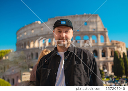 Handsome 30s tourist visiting Colosseum in Rome, Italy. Young man taking photo in front of famous Italian landmark Handsome 30s tourist visiting Colosseum in Rome, Italy. Young man taking photo in front of famous Italian landmark 137207040