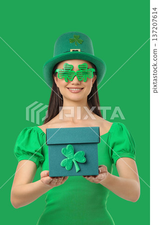 Young woman in green holds a gift for St. Patrick's Day Young woman in green holds a gift for St. Patrick's Day 137207614