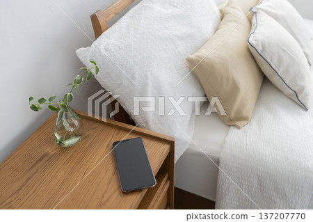 一部智慧型手機放在床頭櫃上 137207770