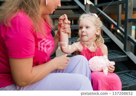 Child girl with cochlear implant with her mother spend time outdoor. Hear impairment and deaf community concept. Deaf and health concept. Disability and inclusion. Copy space 137208652
