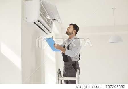 Technician Inspecting Air Conditioner Unit Indoors Technician Inspecting Air Conditioner Unit Indoors 137208662