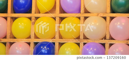 Wide banner of colorful balloons in wooden grid cells for a dart game at a carnival fairground. 137209160