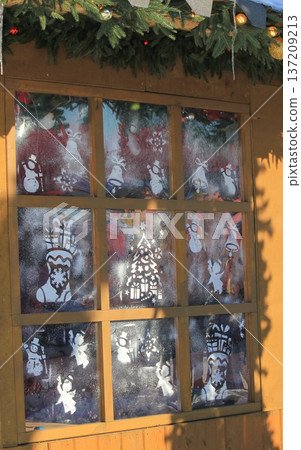 Christmas window decorated with festive stencils and artificial snow at a traditional winter market. Christmas window decorated with festive stencils and artificial snow at a traditional winter market. 137209213