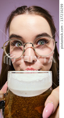 Woman in round glasses drinking light beer close up portrait against purple background 137210299
