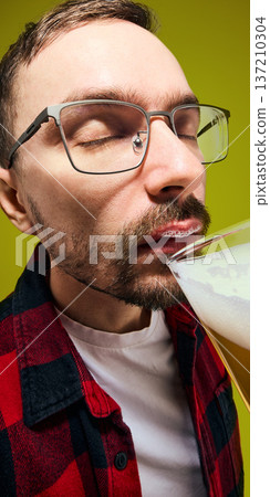 Man with foam mustache drinking light beer close up portrait against yellow background. 137210304