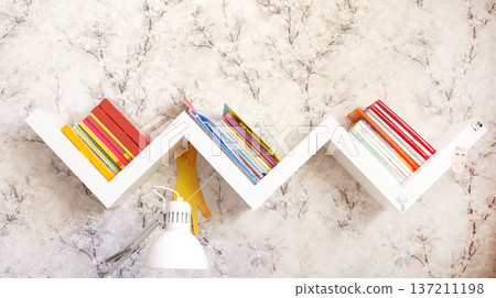 Zigzag bookshelf with books on a light wall Zigzag bookshelf with books on a light wall 137211198