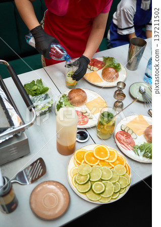 Bartender prepares mojito drinks and burger toppings 137211502