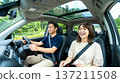 一對面帶笑容的情侶正在享受駕車之旅。一男一女在有天窗的車子裡聊天。 一對面帶笑容的情侶正在享受駕車之旅。一男一女在有天窗的車子裡聊天。 137211508