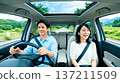一對男女坐在有天窗的車上。車內環境清新宜人,笑容滿面的情侶。 一對男女坐在有天窗的車上。車內環境清新宜人,笑容滿面的情侶。 137211509