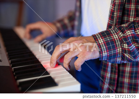 A close-up of hands playing a digital keyboard synthesizer 137211550