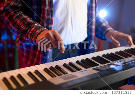 A close-up of hands playing a digital keyboard synthesizer A close-up of hands playing a digital keyboard synthesizer 137211552