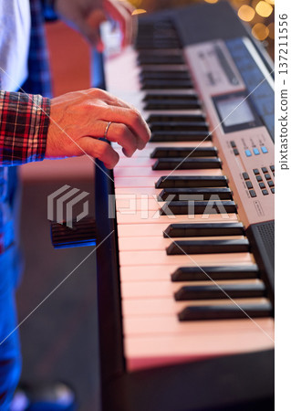 A close-up of hands playing a digital keyboard synthesizer 137211556