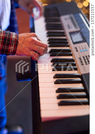 A close-up of hands playing a digital keyboard synthesizer 137211557