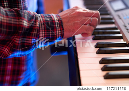 A close-up of hands playing a digital keyboard synthesizer A close-up of hands playing a digital keyboard synthesizer 137211558