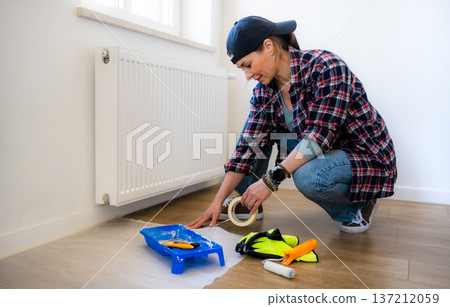 Woman uses tape and tools to work on a home improvement task for renovation living room Woman uses tape and tools to work on a home improvement task for renovation living room 137212059