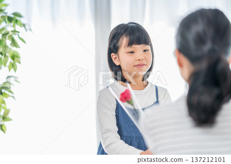 女孩送給母親一朵康乃馨。 137212101