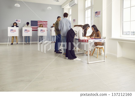 Side view portrait of young girl registering at polling station with American flags on election day 137212160