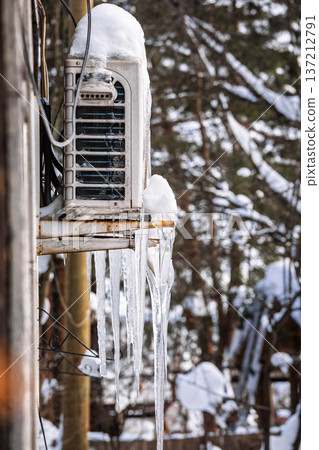 Icicles hanging from exterior HVAC equipment in winter. Shows freezing temperatures, safety concerns, and maintenance needs. 137212791