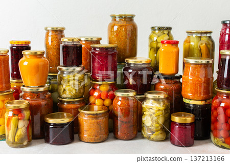 Canned vegetables and fruits are stacked on a shelf, prepared for winter use. Various jars hold different preserves, showcasing careful efforts for storing food during the season Canned vegetables and fruits are stacked on a shelf, prepared for winter use. Various jars hold different preserves, showcasing careful efforts for storing food during the season 137213166