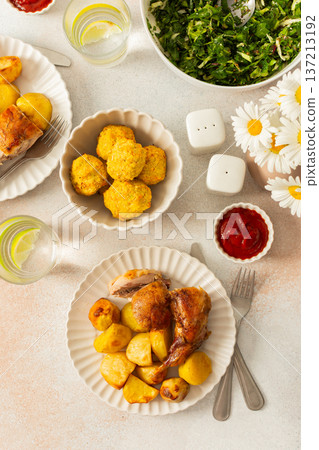 A delicious meal featuring baked rabbit and golden roasted potatoes is served on a round, ridged plate. Accompanying the dish is a glass of water with lemon slices, a small bowl of ketchup A delicious meal featuring baked rabbit and golden roasted potatoes is served on a round, ridged plate. Accompanying the dish is a glass of water with lemon slices, a small bowl of ketchup 137213192