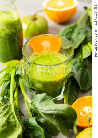 Fresh juice is made using spinach, chard, and broccoli along with oranges and tangerines. A glass of green juice sits by fresh ingredients on a clean kitchen counter Fresh juice is made using spinach, chard, and broccoli along with oranges and tangerines. A glass of green juice sits by fresh ingredients on a clean kitchen counter 137213481