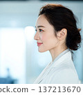 A young woman wearing a white coat looking sideways 137213670