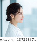 A young woman wearing a white coat looking sideways 137213671