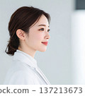 A young woman wearing a white coat looking sideways 137213673