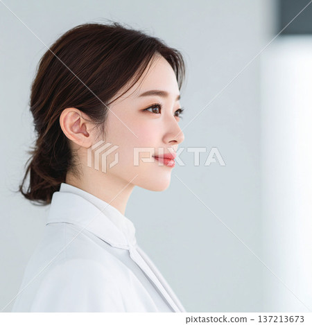 A young woman wearing a white coat looking sideways A young woman wearing a white coat looking sideways 137213673
