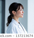 A young woman wearing a white coat looking sideways 137213674