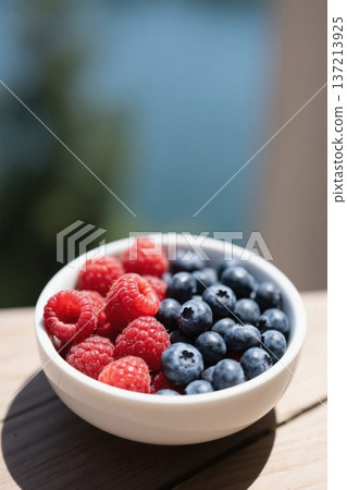Bowls of raspberries and blueberries on a wooden table 137213925