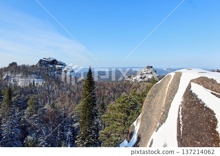 Wide panoramic view of Krasnoyarsk Stolby national park in winter with snow-covered rocks and forest. Nature scenery for travel and tourism. Rocks First Pillar, Second Pillar. View from Fourth Pillar. 137214062