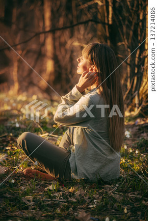 Woman Sitting in Forest Enjoying Warm Sunlight Woman Sitting in Forest Enjoying Warm Sunlight 137214086