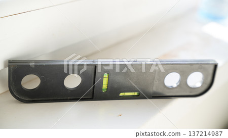 Black spirit level tool placed on white surface during installation work Black spirit level tool placed on white surface during installation work 137214987