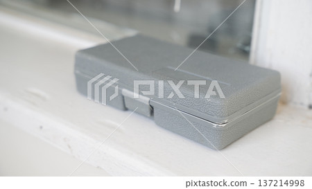 Gray textured plastic tool case placed on white windowsill with soft natural light and minimalist interior background Gray textured plastic tool case placed on white windowsill with soft natural light and minimalist interior background 137214998