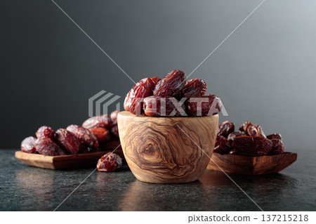 Dates fruit in wooden dish on a black table. Dates fruit in wooden dish on a black table. 137215218