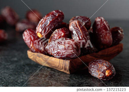 Dates fruit in wooden dish on a black background. Dates fruit in wooden dish on a black background. 137215223