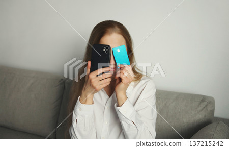 Upset young woman with smartphone, credit bank card, internet fraud, problems with online payments 137215242