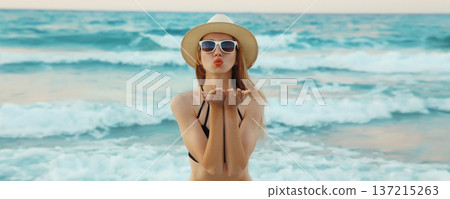 Summer vacation, beautiful young woman blowing kiss in swimsuit, sunglasses, on the beach on sea Summer vacation, beautiful young woman blowing kiss in swimsuit, sunglasses, on the beach on sea 137215263