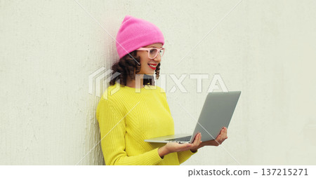 Happy modern young woman working on laptop, freelancer girl looking at computer in colorful clothes Happy modern young woman working on laptop, freelancer girl looking at computer in colorful clothes 137215271