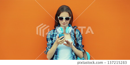 Modern young woman listening to music with smartphone, girl in headphones holding phone Modern young woman listening to music with smartphone, girl in headphones holding phone 137215283