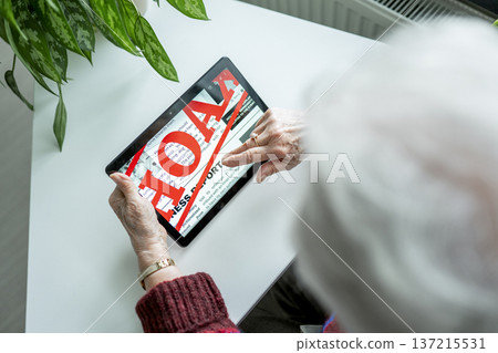 Old person recognizing fake news on digital tablet. 137215531