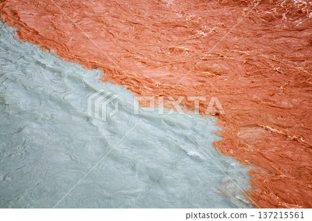 Two rivers meeting with distinct colors, one muddy orange and other light blue. Nature contrast of mixing water bodies Two rivers meeting with distinct colors, one muddy orange and other light blue. Nature contrast of mixing water bodies 137215561